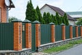 Fence and gate made of metal and bricks on the street near the road Royalty Free Stock Photo