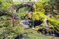 An old stone bridge over some small waterfalls and mossy rocks. Royalty Free Stock Photo