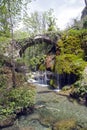 An old stone bridge over some small waterfalls and mossy rocks. Royalty Free Stock Photo