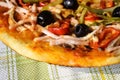 Part of freshly prepared Italian homemade pizza: olives, ham, pepper, sauce, cucumber, cheese.