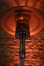 Part of a gas burning patio heater from stainless steel metal against a red illuminated rustic brick wall, selected focus Royalty Free Stock Photo