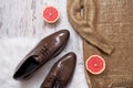 Part of a golden sweater, brown patent leather shoes and grapefruit, wooden background. Fashionable concept.