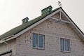 Part of a gray brick house with windows under a green tiled roof Royalty Free Stock Photo