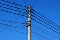 Part of a gray concrete pillar with black wires against a blue sky