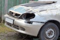 Part of a gray passenger car after an accident with broken headlights