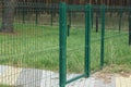 part of a green fence made of metal rods in a net and a closed door