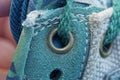 Part of a green leather boot with a gray metal rivet