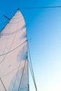 Part of hoisted mainsail of sailboat against blue sky