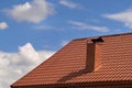 Part of the house with a brown tiled roof and a chimney against the sky. Metal roof Royalty Free Stock Photo