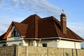 Part of the house under a brown tile roof behind a concrete fence Royalty Free Stock Photo