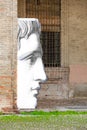 Part of a huge head image depicting the face of a young man on background of an old brick building