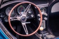 Part of the interior of an oldtimer luxury sports car with steering wheel, speedometer, fuel, clock dials, gear lever, front panel Royalty Free Stock Photo