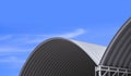 Part of 2 Large Corrugated Steel Dome Roof against blue sky background, low angle view with copy space