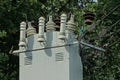 Part of a large gray metal transformer with electric wires on the street