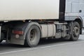 Part of a large gray truck stands on the pavement