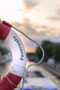 Part of a lifebuoy with rope. In the blurry background you can see a river on which a boat is driving, and the sky lit by the even Royalty Free Stock Photo