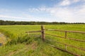 Part of a locked rusty gate before a green meadow Royalty Free Stock Photo