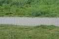 part of an long alley of gray paving slabs among green grass Royalty Free Stock Photo