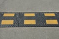 Part of a long dirty black yellow speed bump