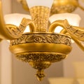 A part of lower part of the gold-colored armature of a classic ceiling chandelier