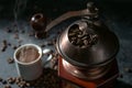 Part of a manual vintage coffee grinder, cup with the hot drink and roasted beans on a dark rustic background, selected focus Royalty Free Stock Photo