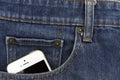 Part of mobile white cellphone in the front pocket of blue denim