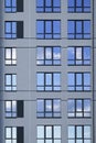 A part of modern residential building facade with reflection of cloudy blue sky in windows Royalty Free Stock Photo