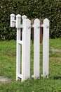 Part of newly made white wooden picket fence with mounted brown metal mailbox surrounded with uncut grass and dark green hedge Royalty Free Stock Photo