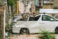 Broken white vehicle buried with old gray bricks from shattered wall. Insurance concept.