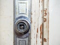 Part of an old door. White paint is coming off the wood. Surface with peeling paint. Destroyed door handle