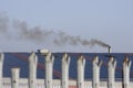 Part of an old fence - close-up. The factory is working, blue roof, and the smoking chimney.