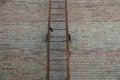 Part of an old iron fire ladder in rust on a brown brick wall