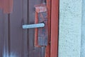 Part of an old red metal door with a gray iron door handle Royalty Free Stock Photo