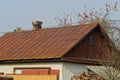 Part of an old rural house with a brown rusty metal roof Royalty Free Stock Photo
