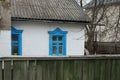 Part of an old rural house with a white wall and a blue window under a gray slate roof Royalty Free Stock Photo