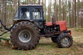 Part of old tractor in the forest to transport timber in the forest among the pine trees. The concept of cutting down trees Royalty Free Stock Photo