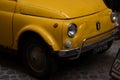 From part of the old vintage yellow fiat car parked in the streets of Rome Italy