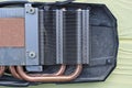 part on a one black disassembled video card with a gray metal radiator and copper brown cooling pipes