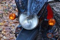 part of one black motorcycle with a white glass round headlight above the wheel