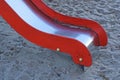 part one red white metal slide over black sand on a playground Royalty Free Stock Photo