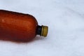 A piece of wet plastic brown bottle on white snow Royalty Free Stock Photo