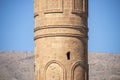 Part of an ornate minaret with raised patterns and letters