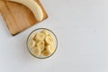 A part of the peeled banana on the cutting board and fresh ripe organic sliced bananas in a glass bowl. Royalty Free Stock Photo