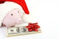 Part of piggy bank with Santa Claus hat and stack of money american hundred dollar bills with red bow Royalty Free Stock Photo