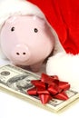 Part of piggy bank with Santa Claus hat and stack of money american hundred dollar bills with red bow Royalty Free Stock Photo