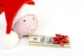 Part of piggy bank with Santa Claus hat and stack of money american hundred dollar bills with red bow Royalty Free Stock Photo