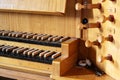 Part of a pipe organ console with two keyboards or manuals and wooden stop knobs for registration