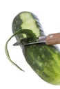 Cucumber being peeled with a wooden peeler and a Bark from peeled cucumber on white
