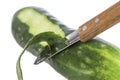 Cucumber being peeled with a wooden peeler and a Bark from peeled cucumber on white