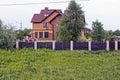 Part of a private house behind a fence with a gate in green vegetation Royalty Free Stock Photo